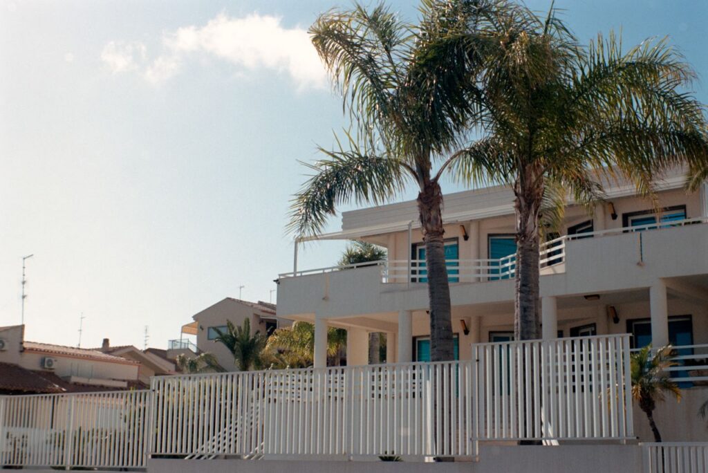 Contemporary villa with palm trees and blue sky in Sicily, Italy highlighting Mediterranean architecture.